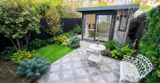 Wide angle of small garden with garden room at the rear and grey decorative patio at the front