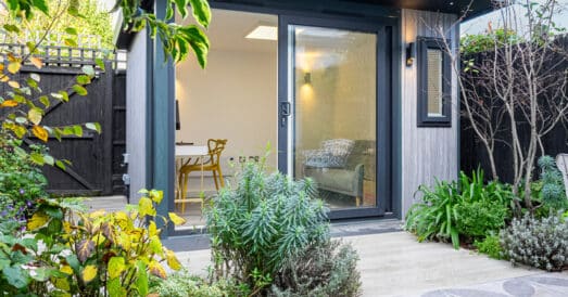 Grey composite clad garden room with lush green garden and grass in the foreground